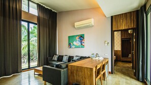 A modern living room with a sofa, wooden dining table, and a painting on the wall. - Lumphawa Amphawa (Samut Songkhram)