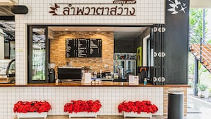 A coffee shop with a menu board, a counter, and potted plants. - Lumphawa Amphawa (Samut Songkhram)