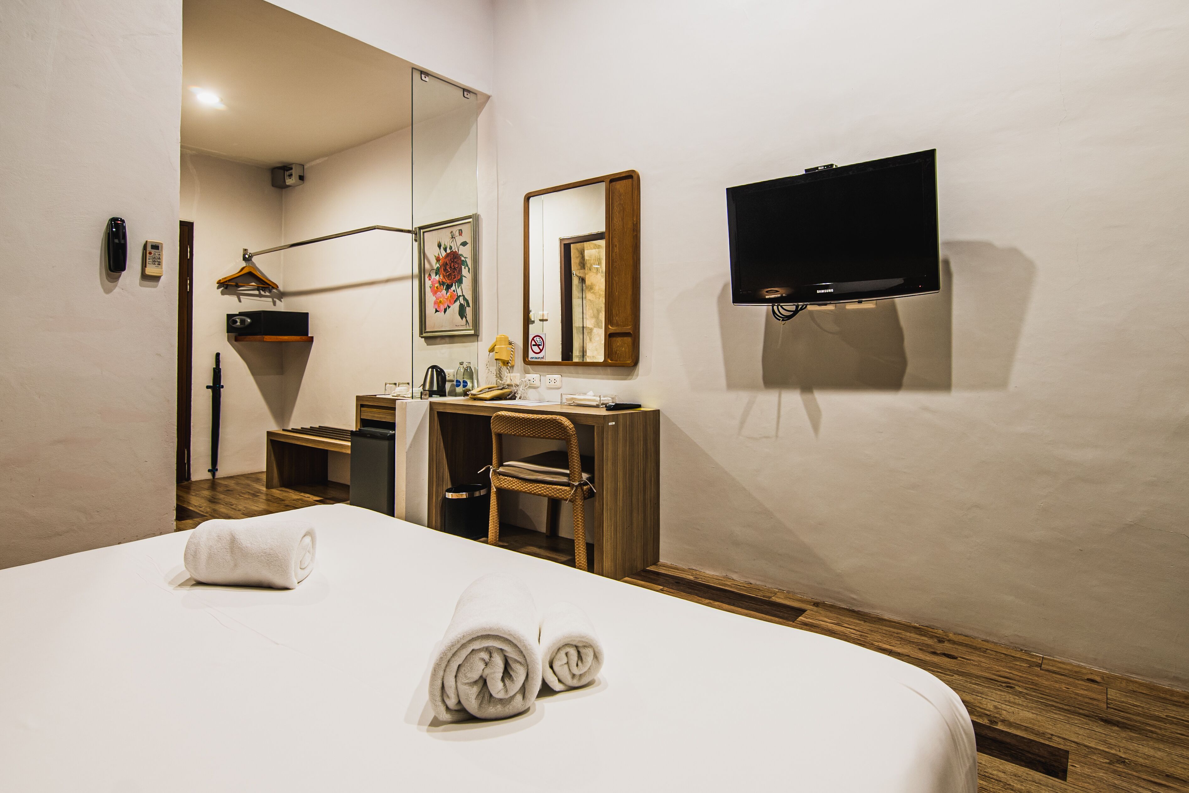 Habitación de hotel con cama, escritorio, silla, televisor, espejo y teléfono.