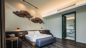 A modern bedroom with a large bed, bedside tables, a small sofa, and a unique wall art piece. - Lumphawa Amphawa (Samut Songkhram)