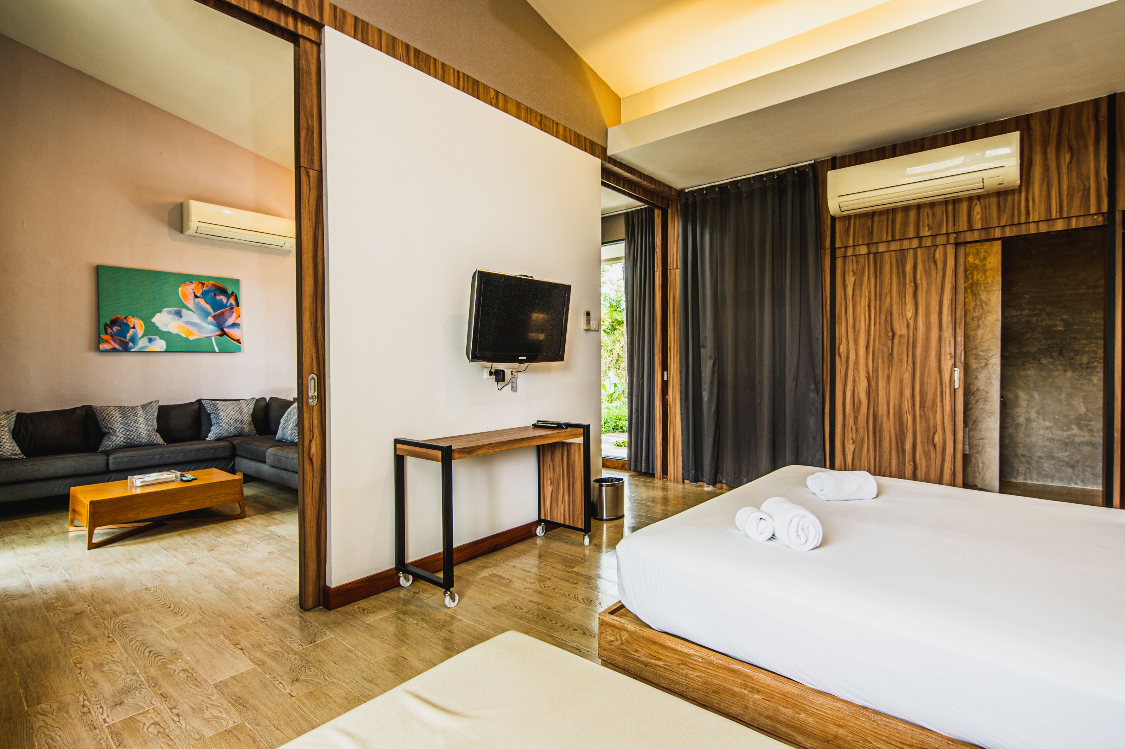 Habitación de hotel con cama, escritorio, televisor, un cuadro y vista al exterior.