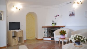 Una sala de estar con televisor sobre un mueble de madera, una chimenea y dos sillones.