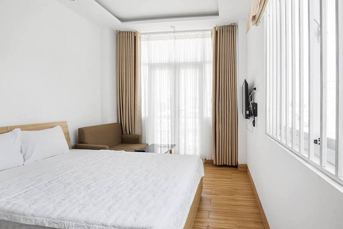 A hotel room with a large bed, a chair, a small table, and a TV mounted on the wall.