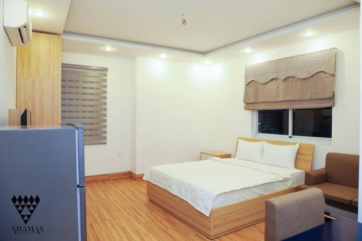 A modern hotel room with a wooden bed, a small seating area, and a window with a view.