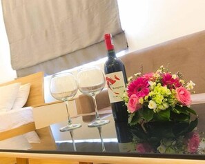 A glass table with a bottle of Kangaroo wine, two wine glasses, and a bouquet of flowers.