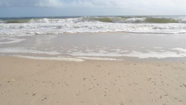 A beach with waves approaching the shore.