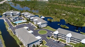 A multi-story hotel with a central courtyard, parking lot, and a lake with boats.