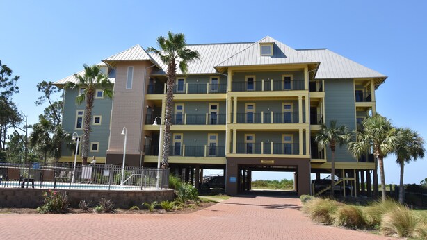 A multi-story hotel with a flat roof, balconies, and a paved entrance area with landscaping. - Fall is spectacular on the Cape! Book your trip now (Port St Joe)