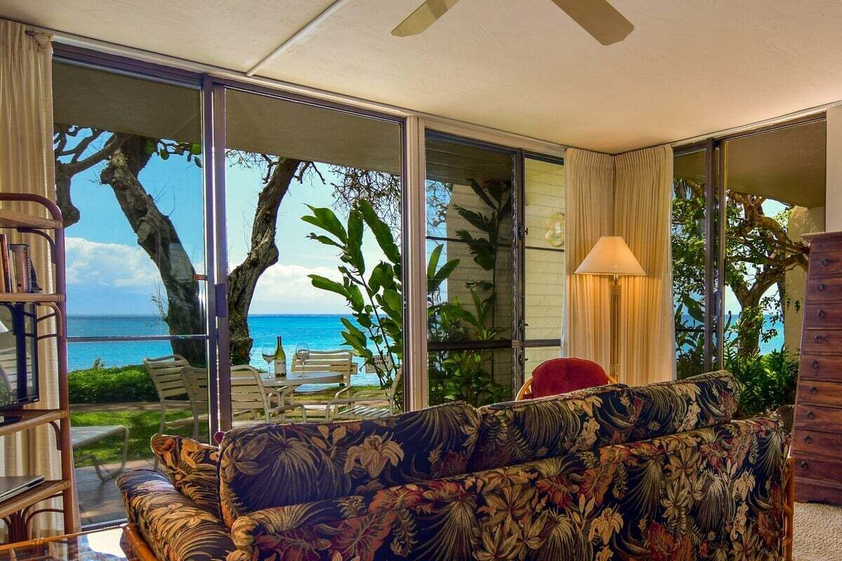 Een kamer met een bank, gericht op een grote glazen schuifdeur met uitzicht op de oceaan.