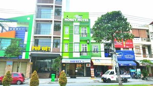 A multi-story building with a green facade and a sign for "Honey Hotel" on the second floor.