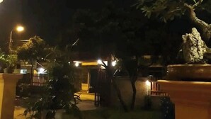 A nighttime outdoor area with a paved walkway, potted plants, and a stone sculpture. - Ninh Binh Riverside Homestay 2 (Ninh Binh)
