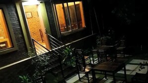 An outdoor seating area with tables and chairs, a staircase, and a brick wall with windows. - Ninh Binh Riverside Homestay 2 (Ninh Binh)