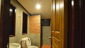 A bathroom with a toilet, sink, and a brick accent wall.