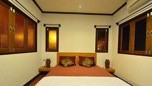 A bedroom with a large bed, two nightstands, a wooden headboard, and two windows with decorative glass panels.