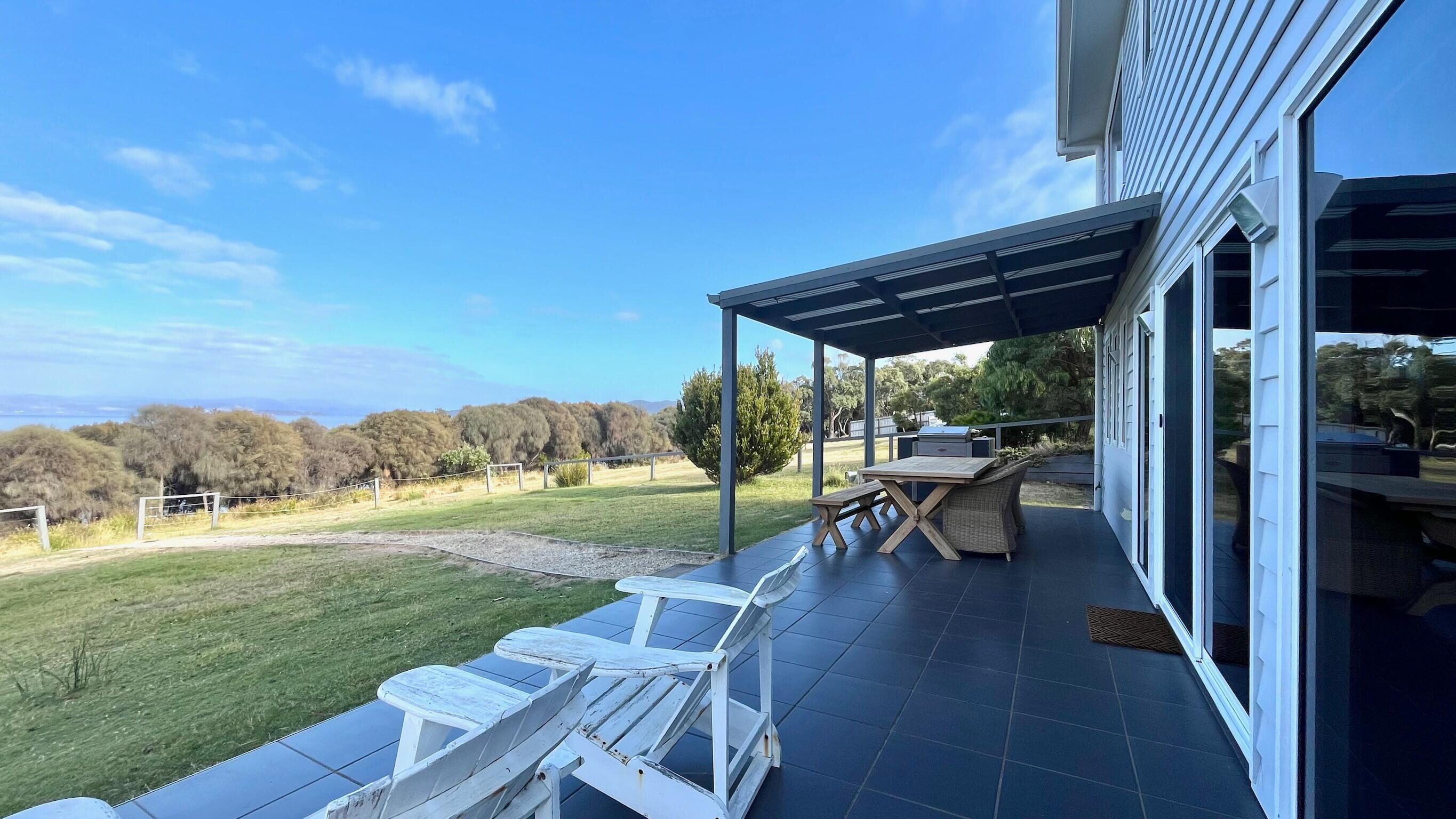 Une terrasse extérieure couverte avec vue sur la campagne, une table et deux fauteuils de relaxation.