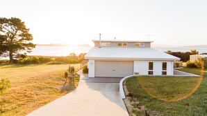 A modern two-story house with a garage, a driveway, and a grassy yard. - Manfield Seaside Bruny Island (Alonnah)