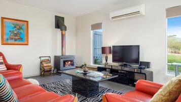 Una sala moderna con chimenea, televisor de pantalla plana y sofás de cuero rojo.