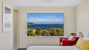 A hotel room with a large window offering a scenic view of the sea and trees. - Manfield Seaside Bruny Island (Alonnah)