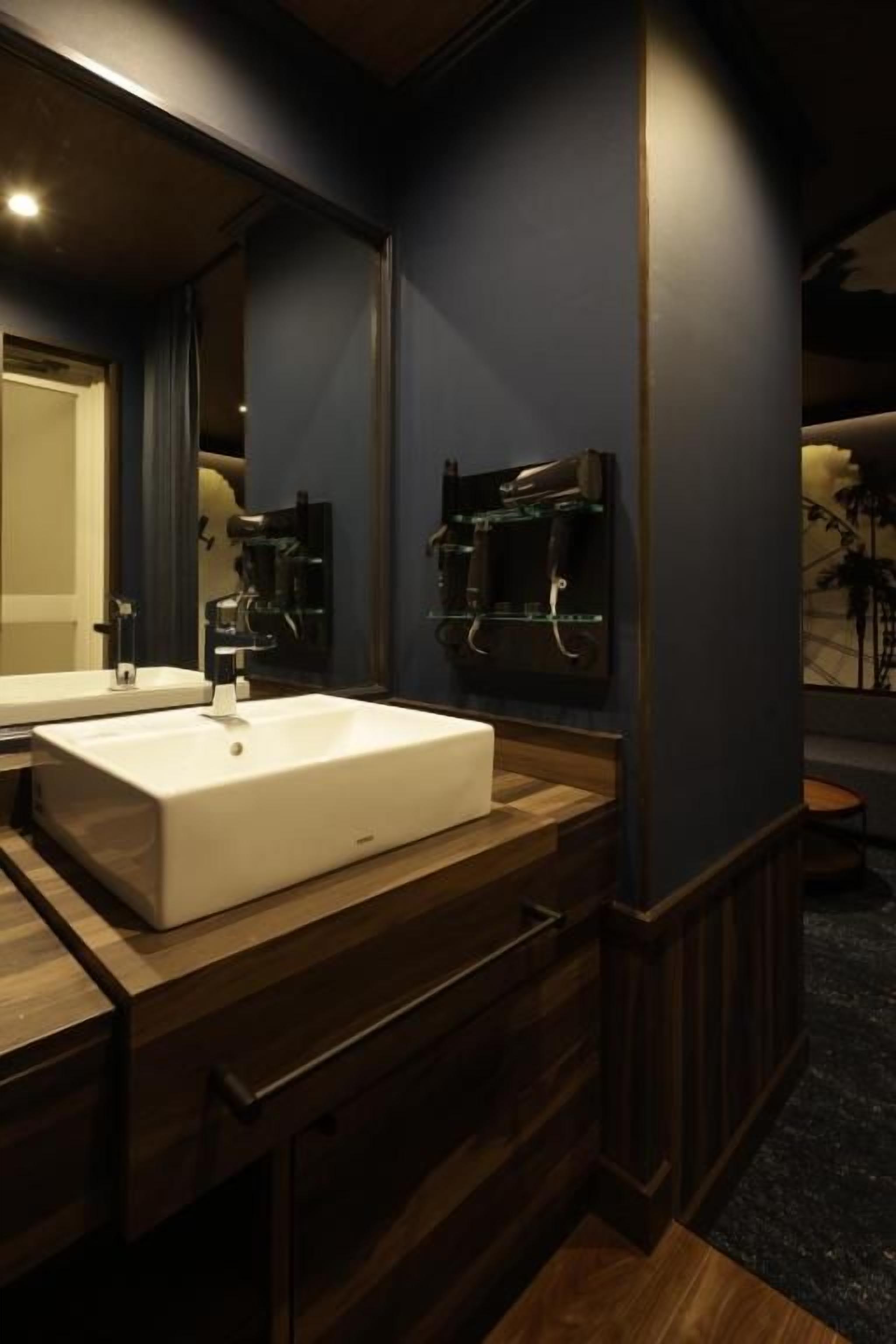 Een badkamer met een groot wit wastafelmeubel, een houten opbergkast en een spiegel.