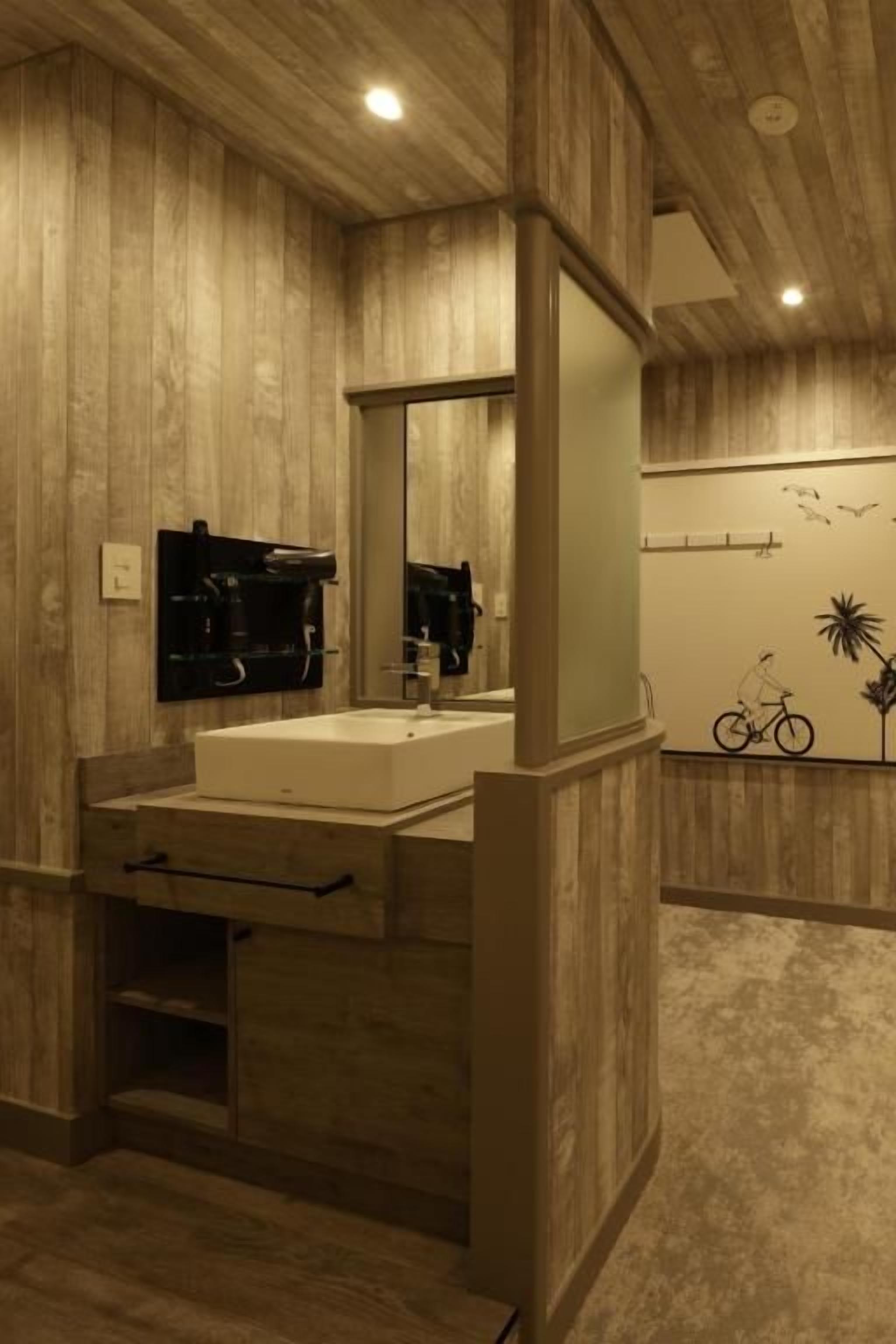 A bathroom with a wooden wall paneling, a sink with a mirror, and a towel rack.