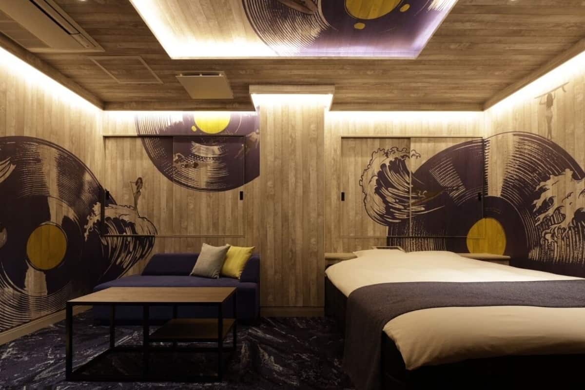 A room with a wooden ceiling, a bed, a sofa, and a table.
