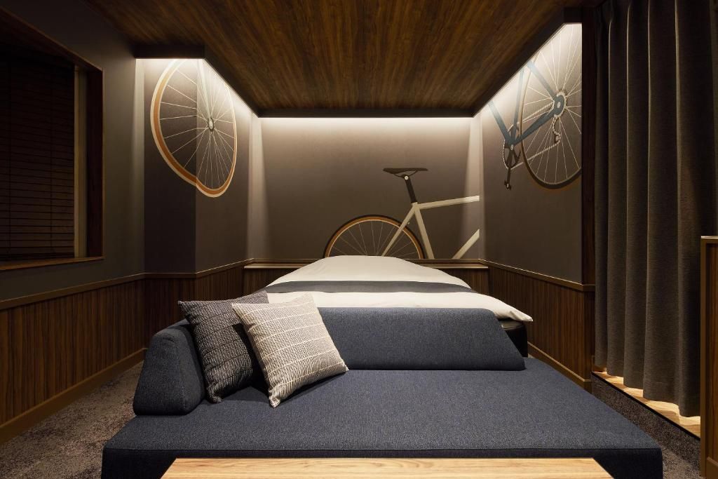A bedroom with a bed, a bicycle, and a wall-mounted bicycle wheel.