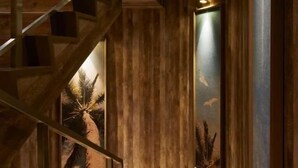 Un escalier en bois mène à une pièce dotée d’une grande fenêtre offrant une vue sur les palmiers.