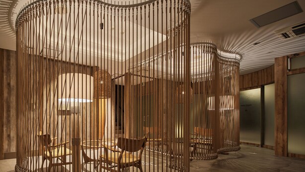 Un intérieur moderne avec un espace salon circulaire délimité par des barrières faites de cordes.