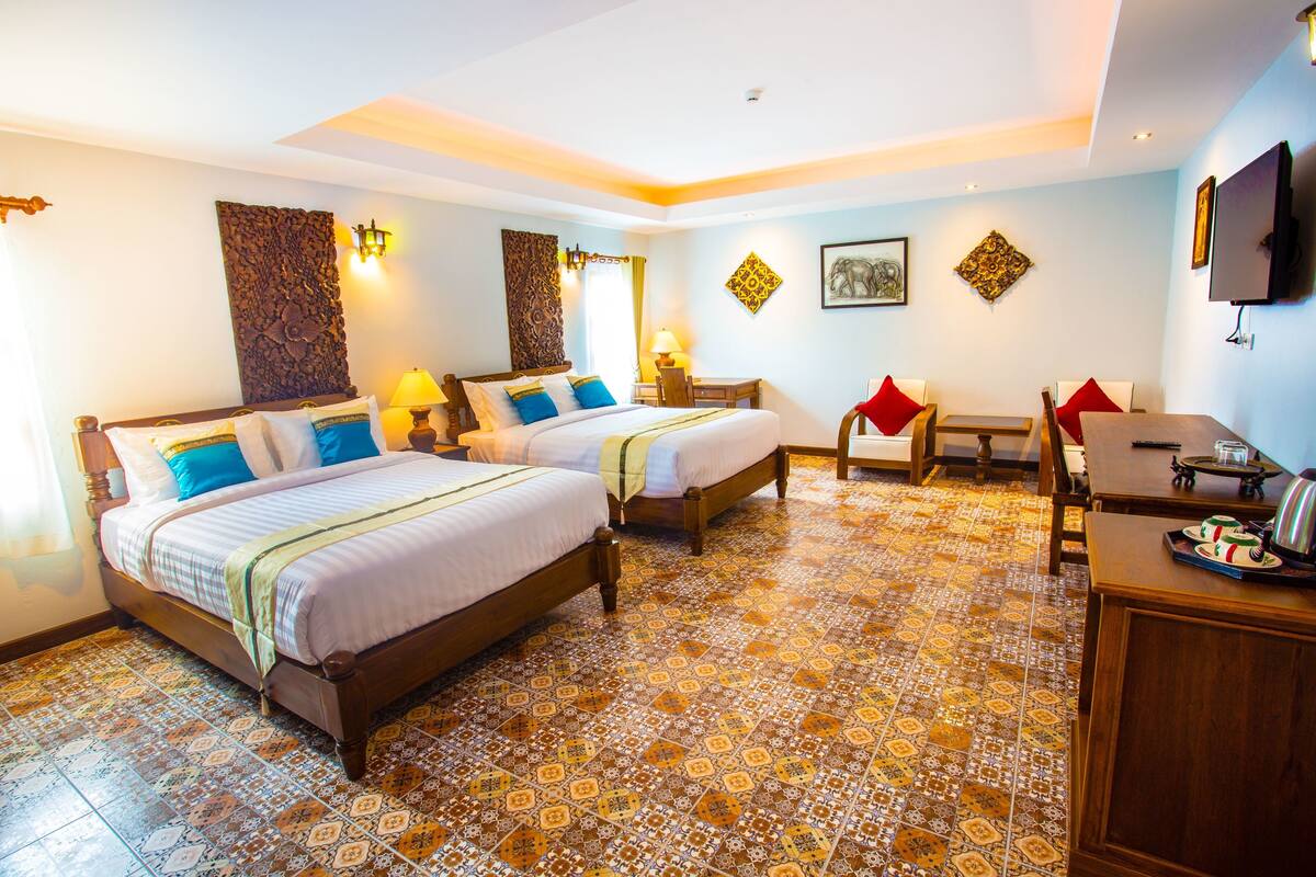 Une chambre d’hôtel avec deux lits, un bureau, une chaise et un téléviseur.