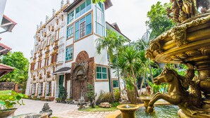 Un bâtiment historique à l’architecture riche et ornée, doté d’une fontaine et d’un jardin bien entretenu.