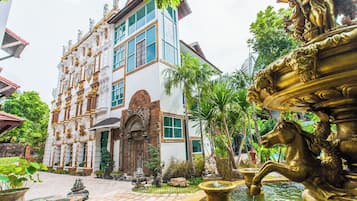 Un edificio con detalles arquitectónicos ornamentales, una fuente y un jardín bien cuidado.