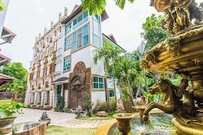 Un bâtiment doté d’éléments architecturaux décoratifs, d’une fontaine et d’un jardin bien entretenu.