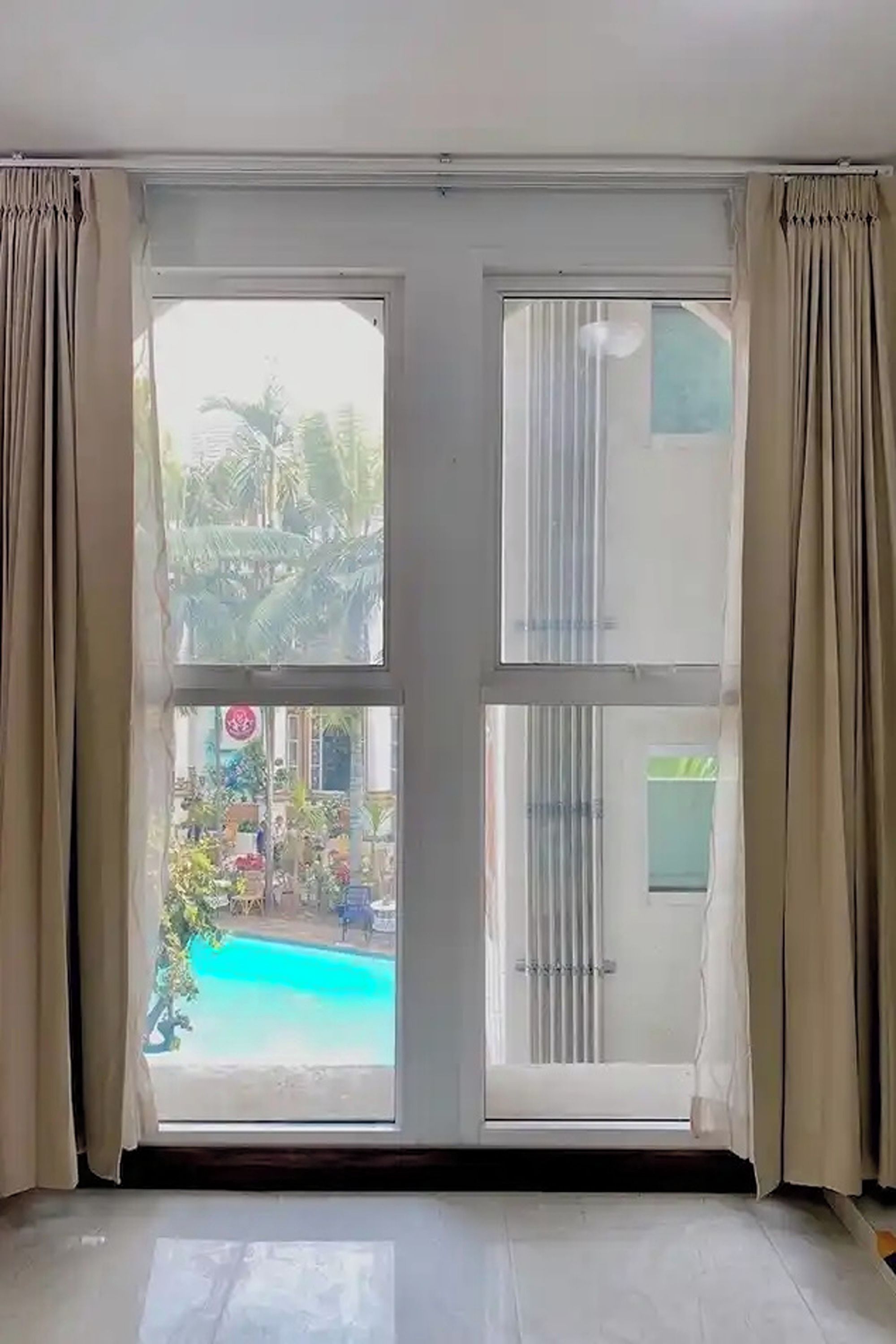 A room with a large sliding glass door leading to an outdoor area with a pool and greenery.
