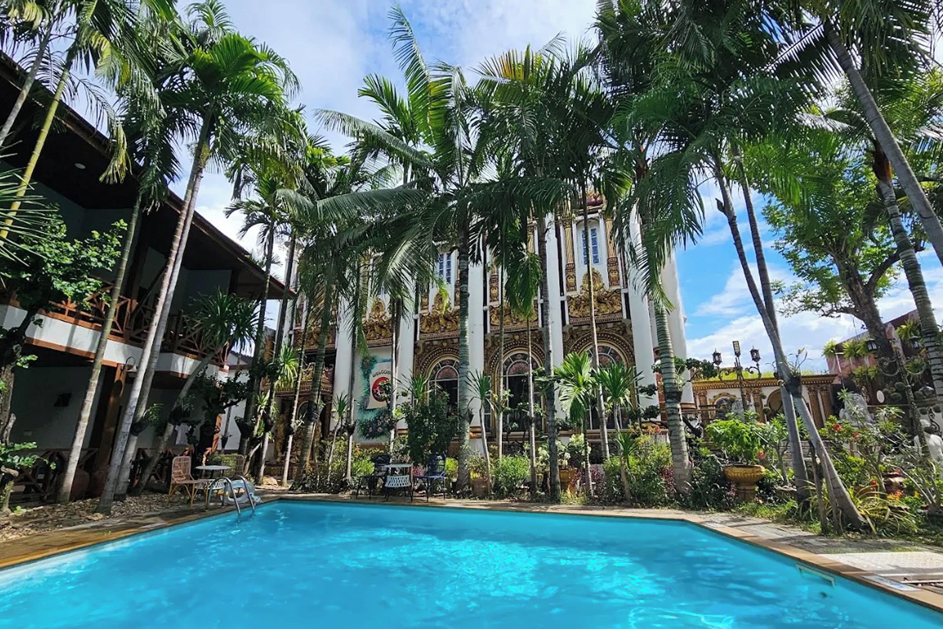 Una piscina rodeada de palmeras y un edificio con arquitectura decorada.