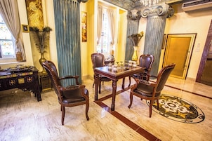 Un comedor formal con piso de mármol, una mesa de madera y cuatro sillas tapizadas.