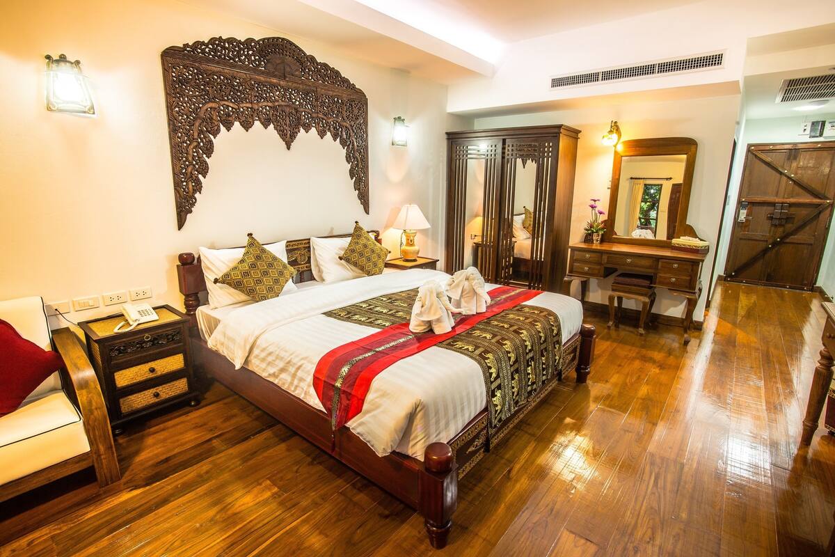Une chambre spacieuse avec un grand lit, des meubles en bois et un miroir.