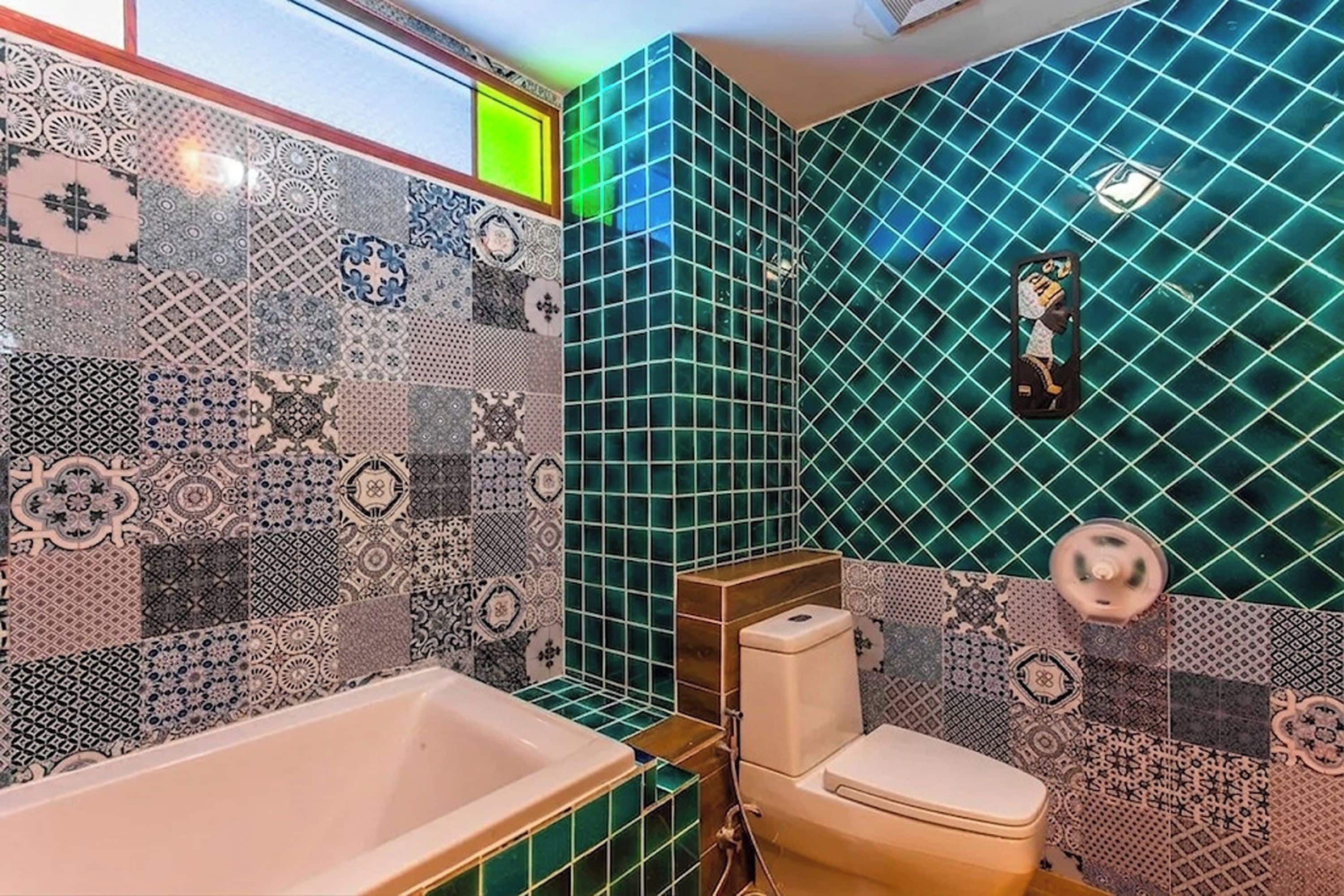 A bathroom with a bathtub, toilet, and a wall with a geometric tile pattern.