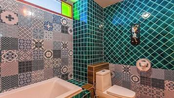 A bathroom with a bathtub, toilet, and a wall with a geometric tile pattern.