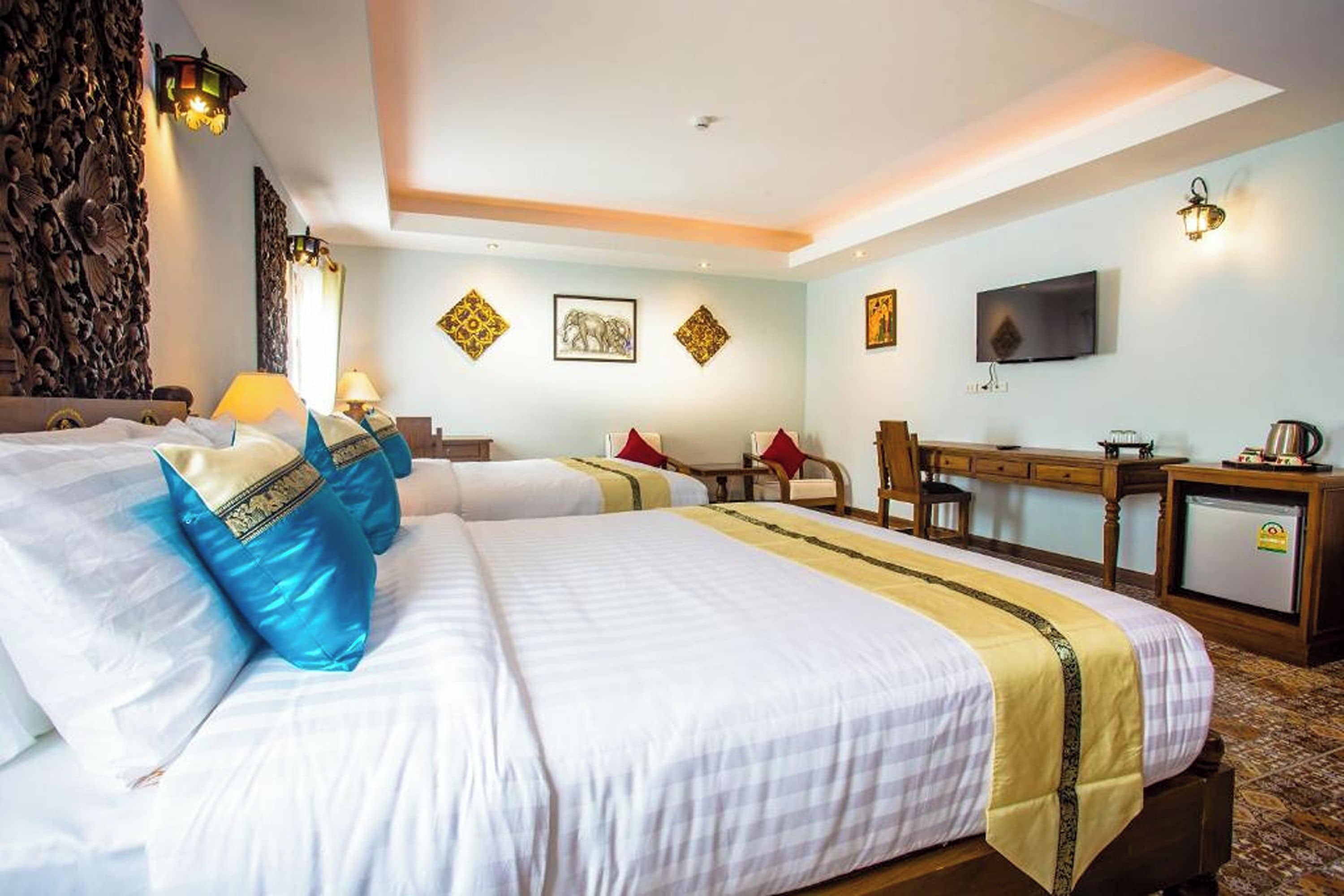 A hotel room with two beds, a desk, a television, and decorative wall art.