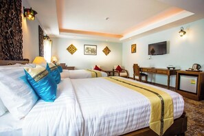 Une chambre d’hôtel avec deux lits, un bureau, une télévision et des œuvres d’art décoratives au mur.