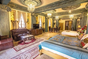 Una habitación de hotel lujosa con una cama grande, un sofá, un televisor y un comedor.