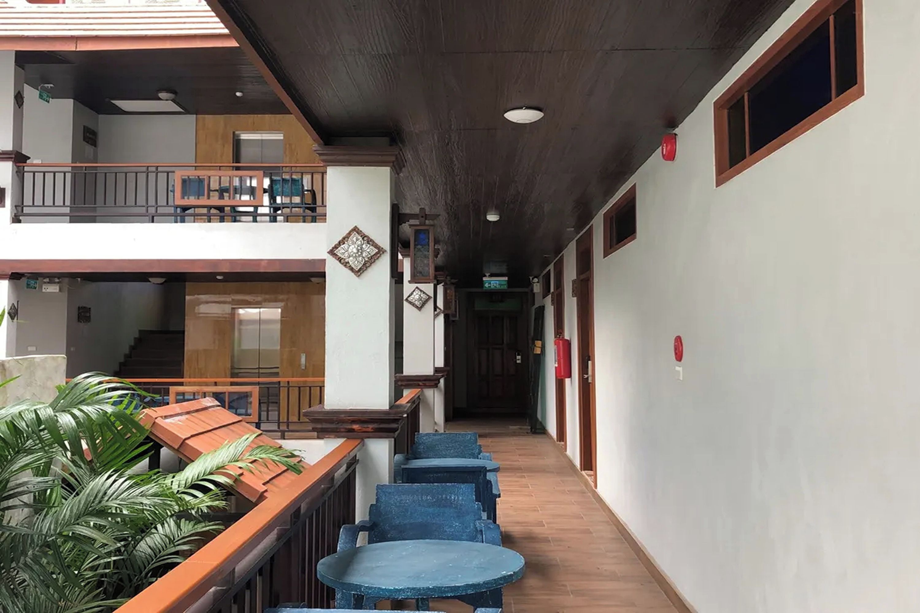 Un pasillo con un banco de madera y sillas azules, una escalera y una puerta al final.