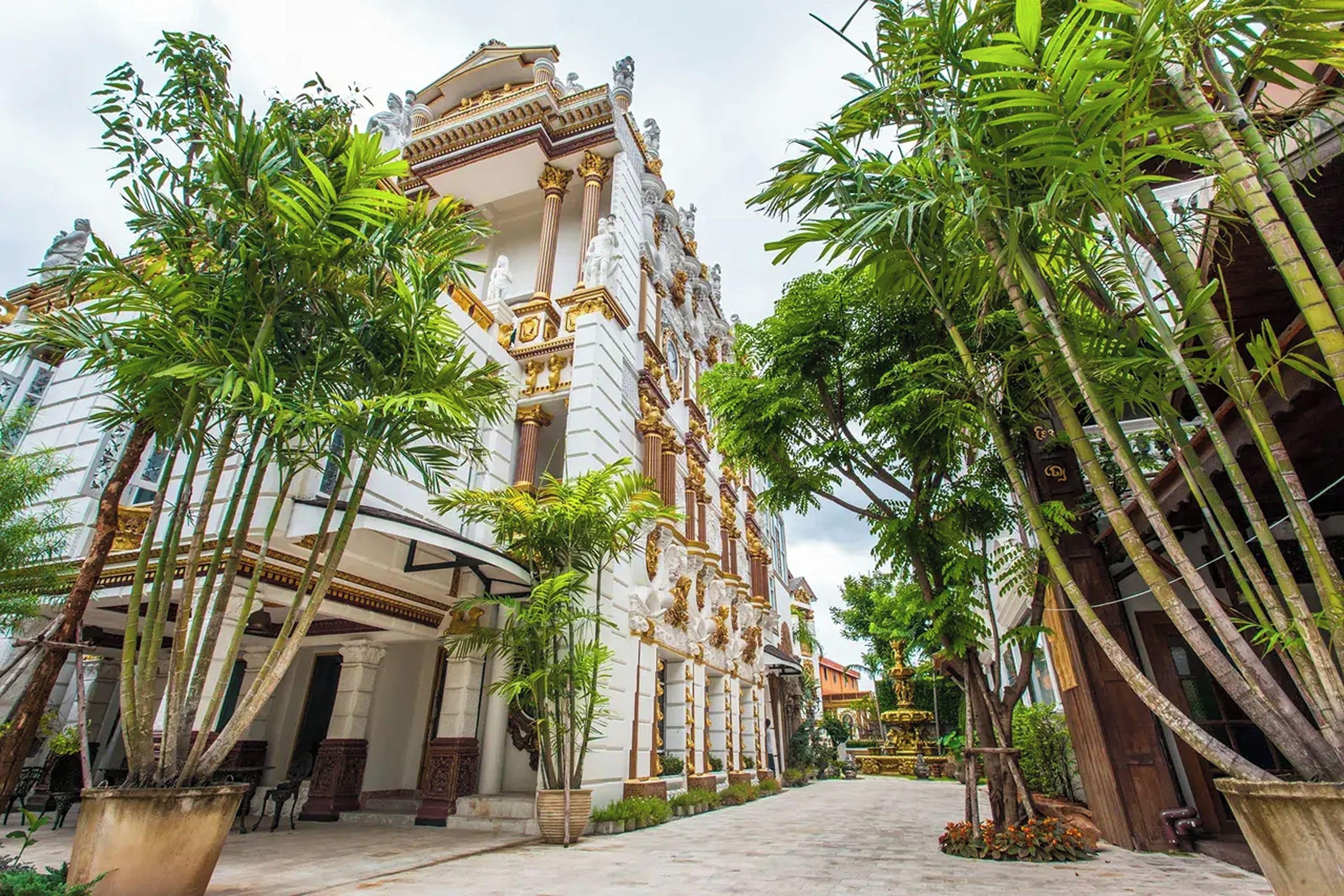 A building with classical architecture, surrounded by lush greenery and palm trees.