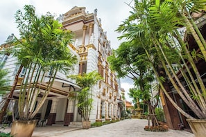A building with classical architecture, surrounded by lush greenery and palm trees.