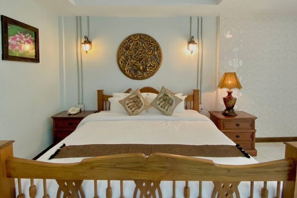 Une chambre à coucher avec un lit en bois, deux tables de chevet, une lampe fixée au mur et un élément décoratif mural.
