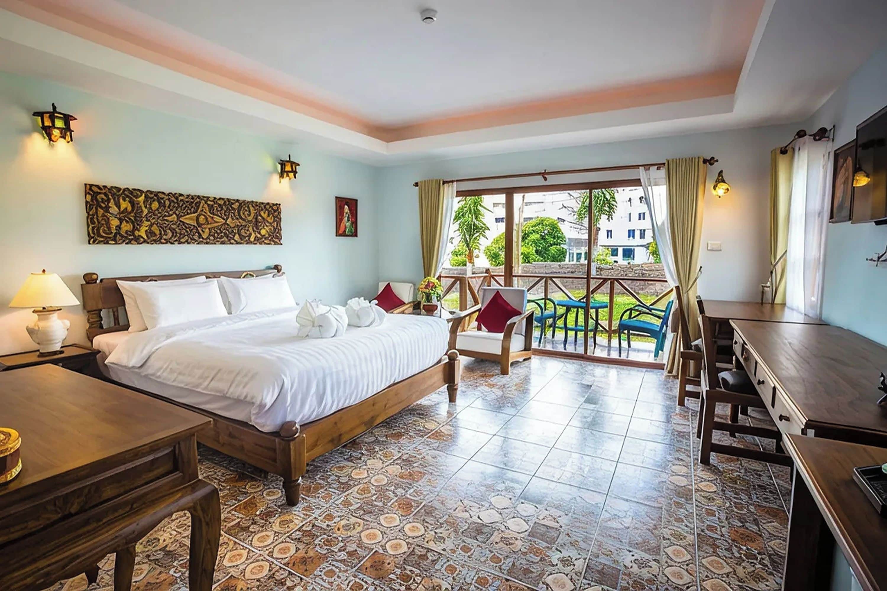 A hotel room with a bed, a desk, a chair, and a balcony with a view of the outside.