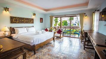 A hotel room with a bed, a desk, a chair, and a balcony with a view of the outside.
