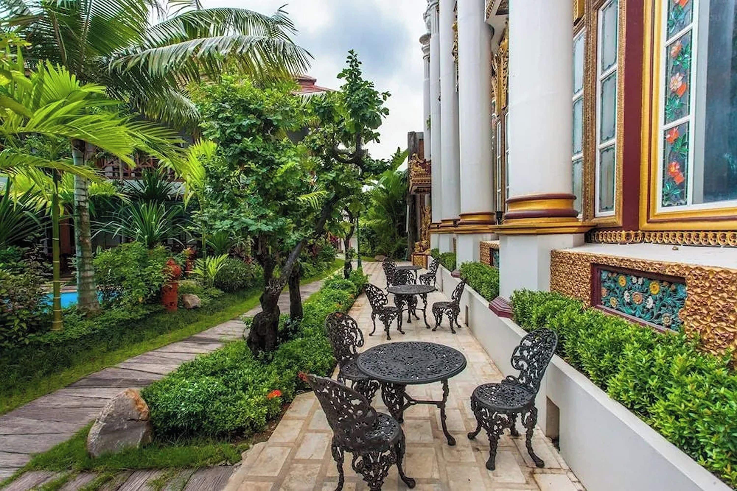A courtyard with a paved walkway, outdoor seating, and lush greenery.