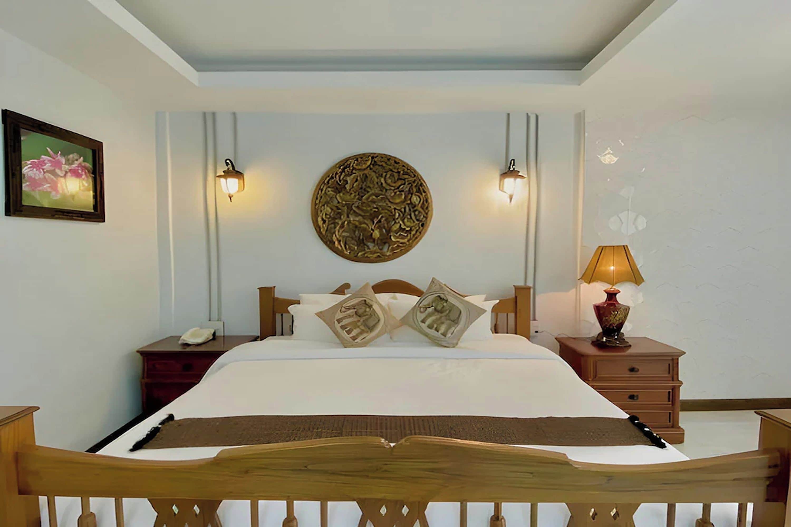 A hotel room with a bed, bedside tables, a lamp, and a decorative wall piece.