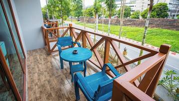 A balcony with wooden railings, a blue table, and matching chairs.